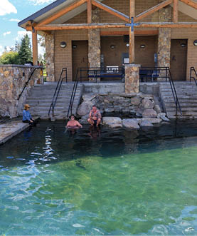 Two people are sitting in a pool, one on the left and one on the right. They are both naked, and there are steps leading into the pool. AI generated content
